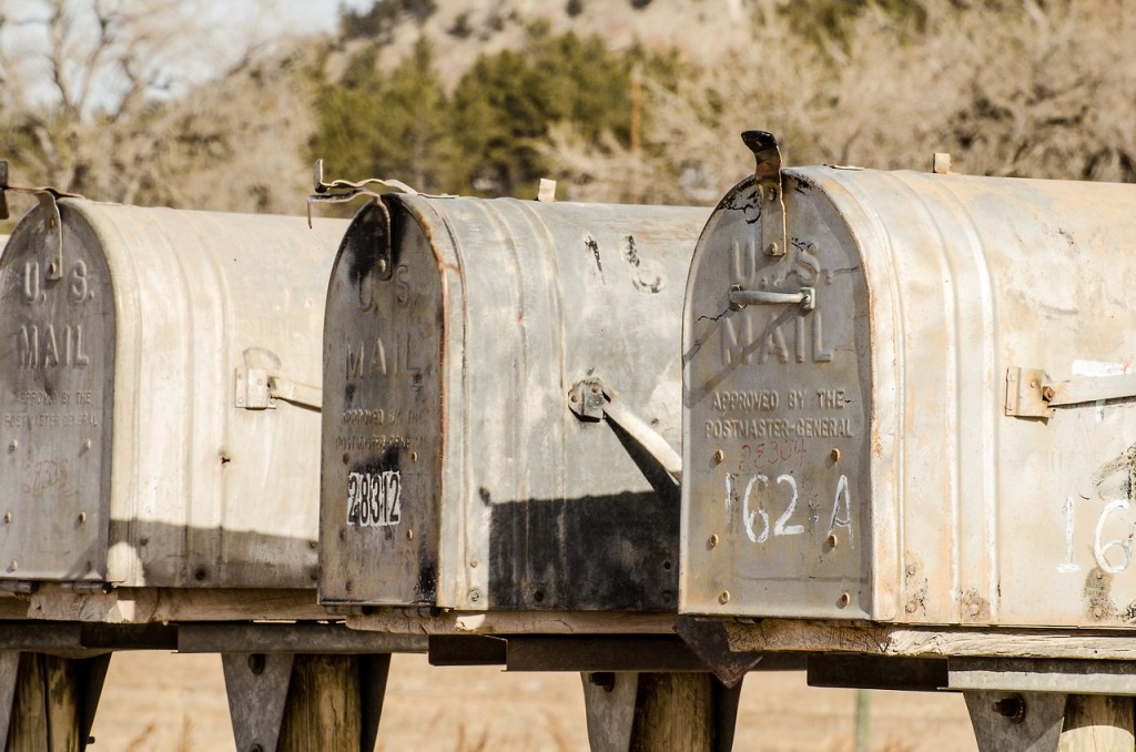 3 old metal mail boxes on wooden posts.