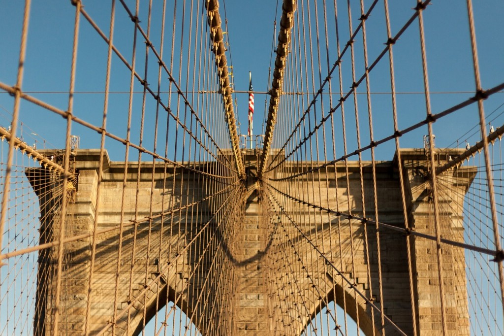 The Brooklyn bridge with an American flag on the top.