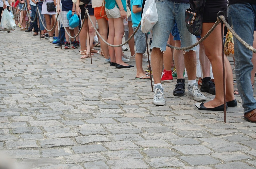 Many people standing in line with a rope behind them.