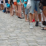 Many people standing in line with a rope behind them.