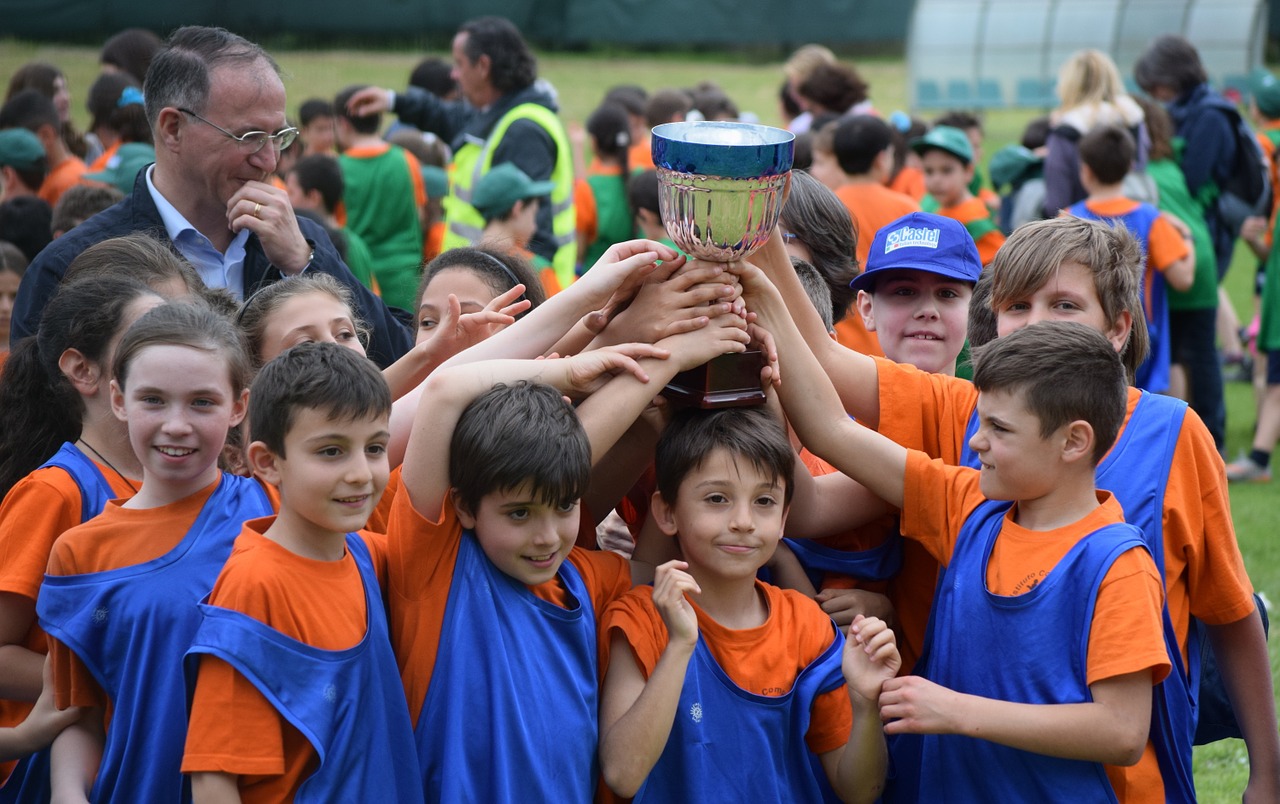 A team of children and their coach holding up a trophy.