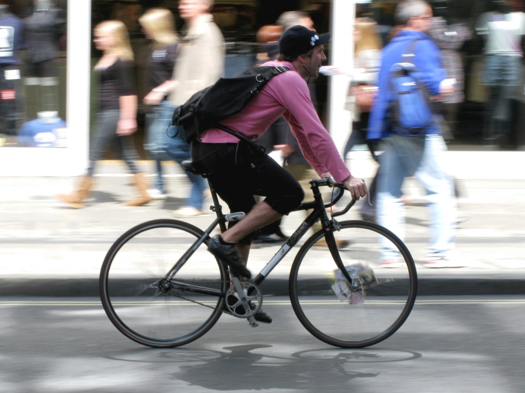 Bicycle courier riding down street.