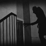 Shadow of a creepy man reaching towards a door at the top of a staircase.