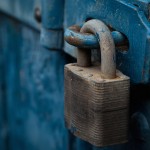 A weathered, blue door locked with a large chain and a padlock.