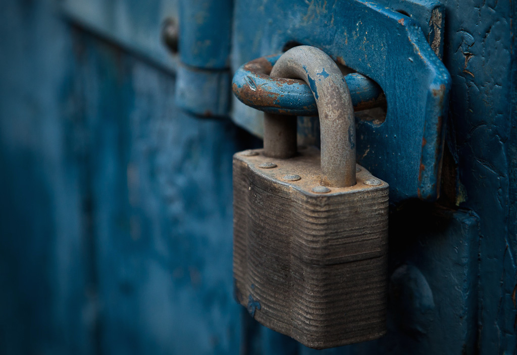 A weathered, blue door locked with a large chain and a padlock.