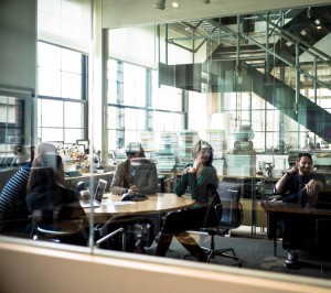 People sitting around a table in an office. They are laughing and looking in the same direction.