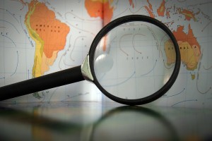 A magnifying glass laying on a table over the ocean and part of Australia on a map.
