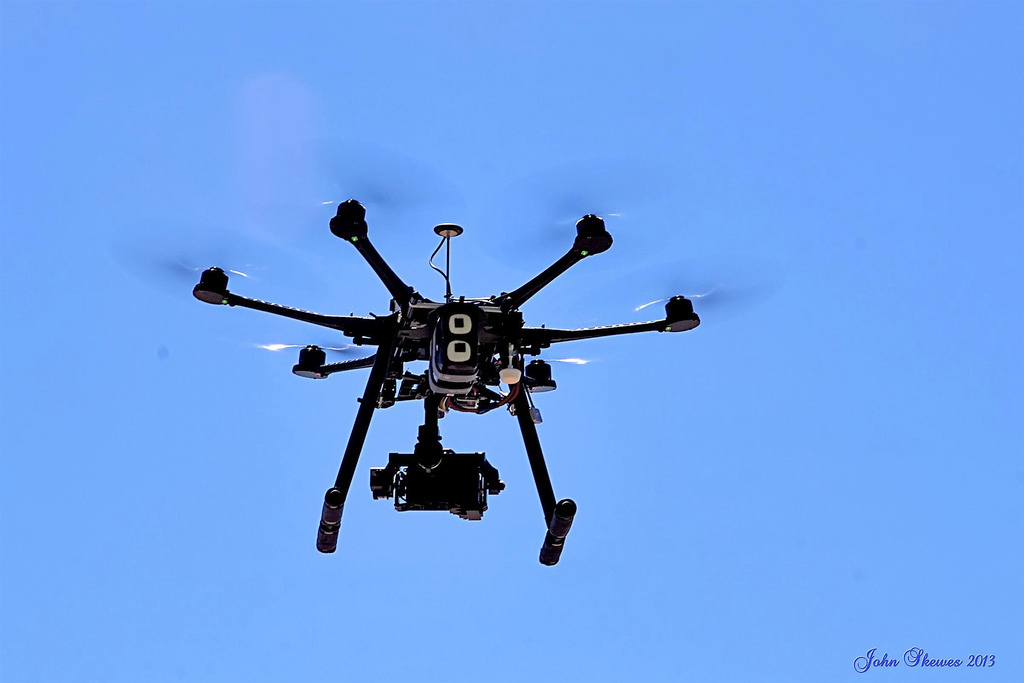 A drone hovering in a blue sky.