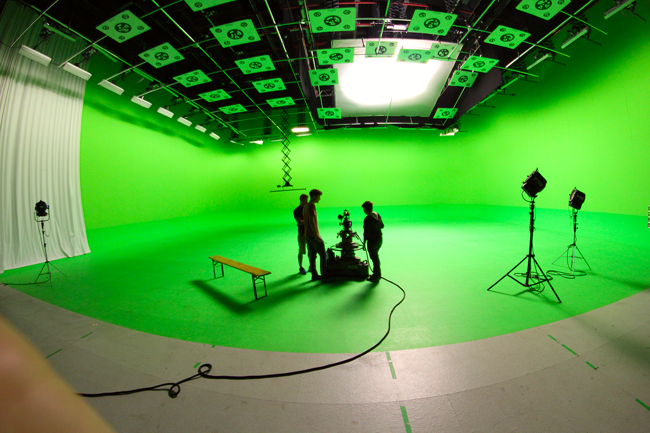A Stargate studios film stage with a huge green screen and film makers setting up.