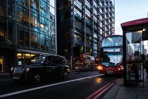 London street with a double decker bus at a bus stop.