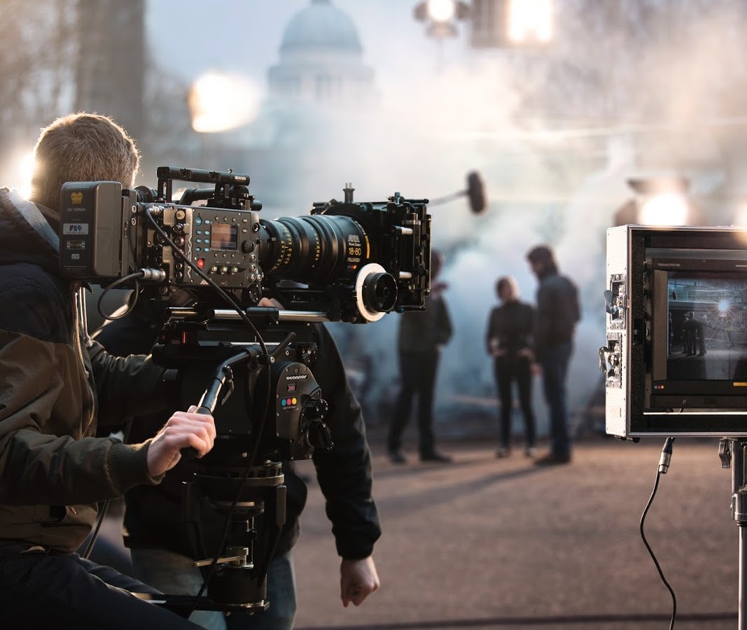 A team filming a movie on a street with large buildings in the background.