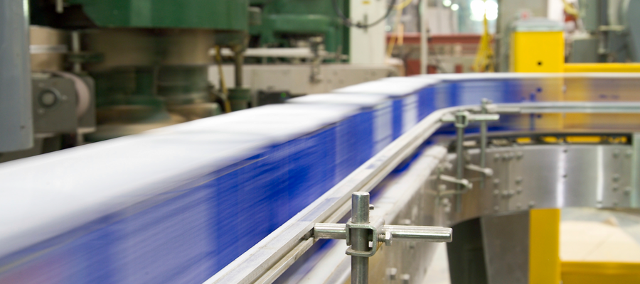 Photograph of blue boxes whizzing by on a factor conveyor system.