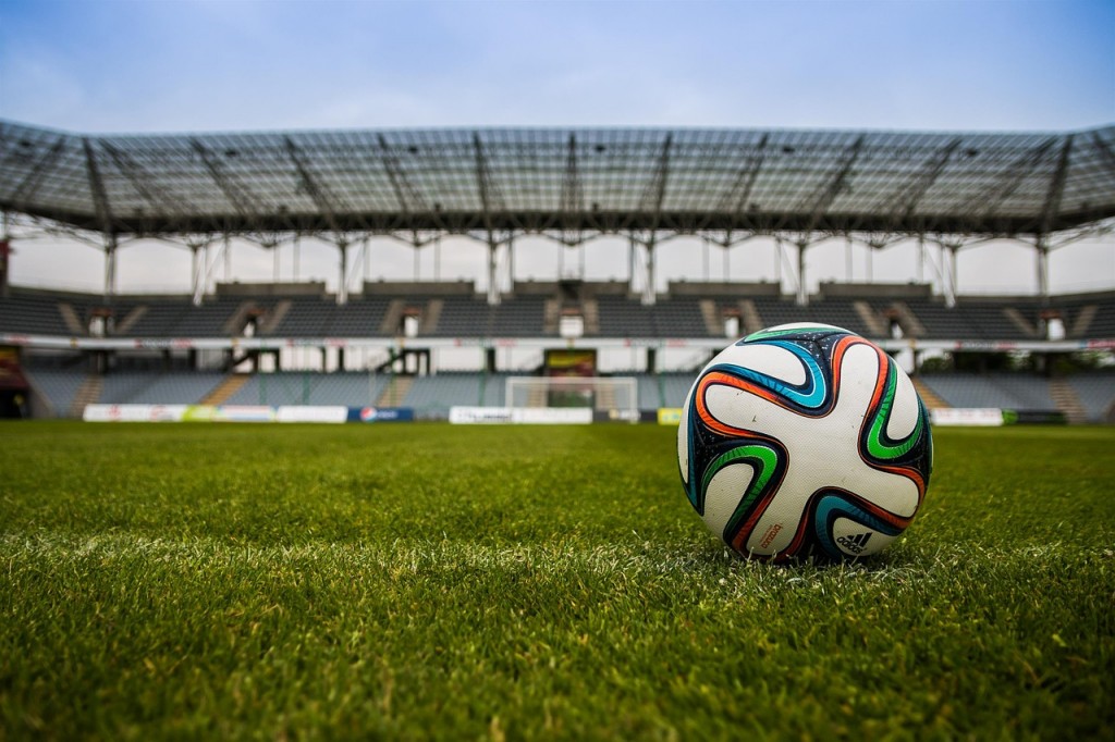 A closeup of a soccer ball on a field in a large stadium.