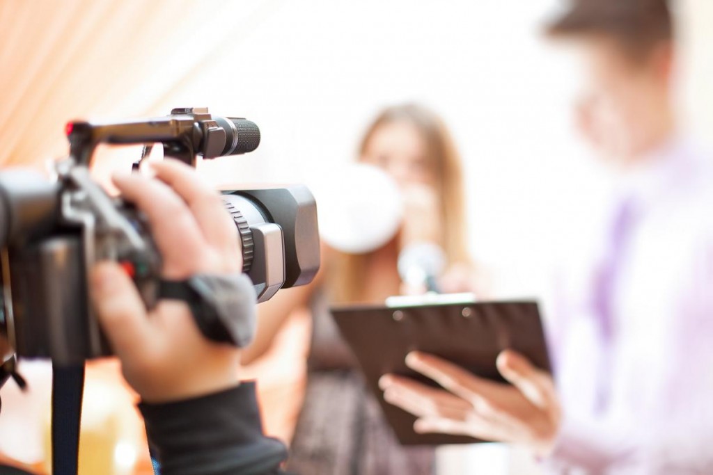 A man filming another man and a woman talking for a corporate video.