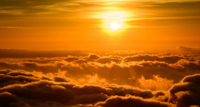 The sun setting above the clouds.