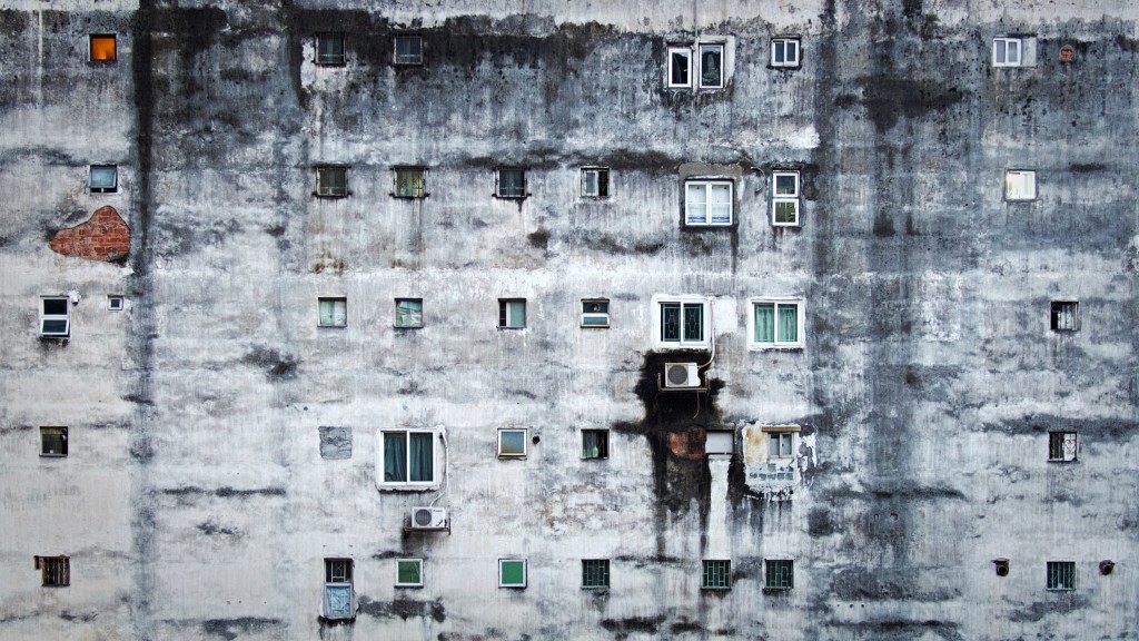 The side of a large, rundown apartment building, with many windows.