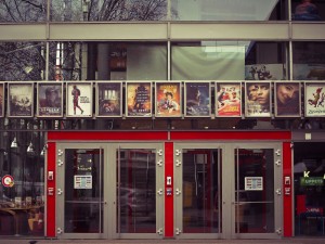 The front entrance to a movie cinema with many movie posters across the front.