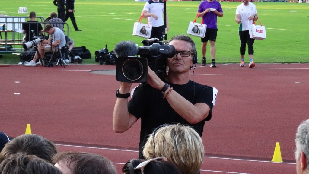 A man filming the crowd at a sporting event.