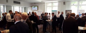 Many men standing around small tables with drinks, at the TVB Europe Exhibit Networking event.