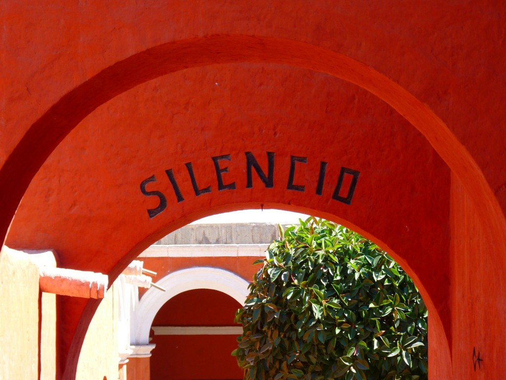 Red arches of a building with the word Silencio carved into them.