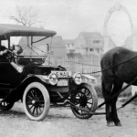 A man driving a model T Ford with a horse hooked up to the front of it.