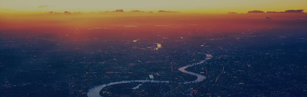An aerial view of the Thames winding through London at sunset.