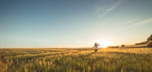 A woman running in a field at sun rise.