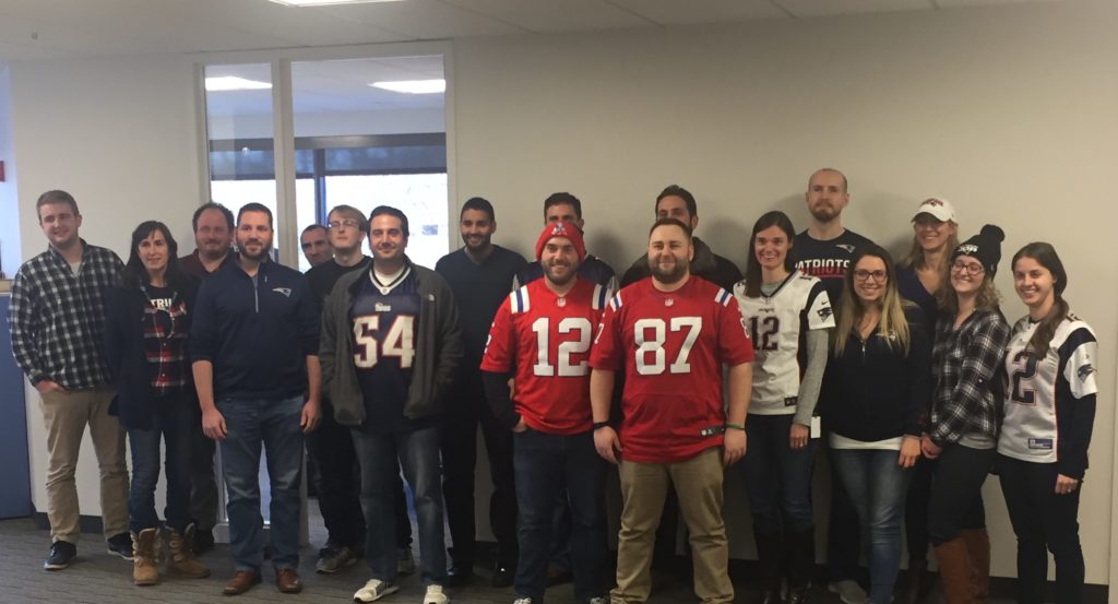 A group of Signiant employees wearing Patriot jerseys and other gear.