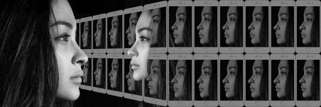 A young woman with dark hair staring into the distance, and there's rows of white tablets with her face on them.