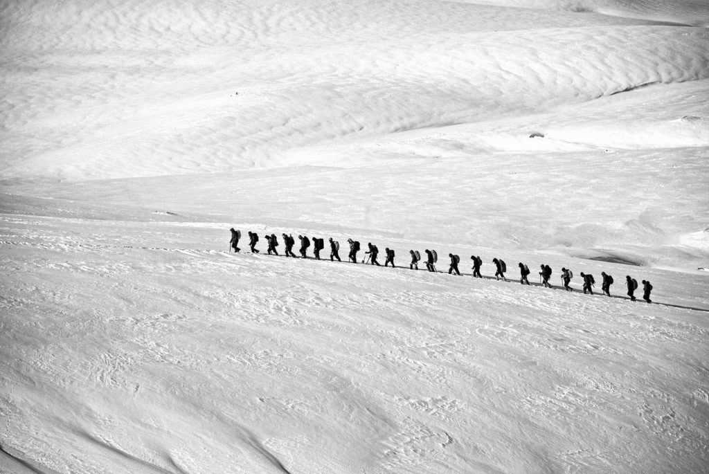 A group of people trekking through snowy mountains.