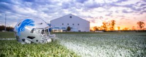 A Detroit Lions football helmet on a football field at twilight.