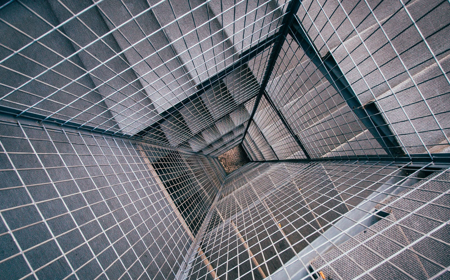 A metal fence around the center of the open space between a spiral staircase.