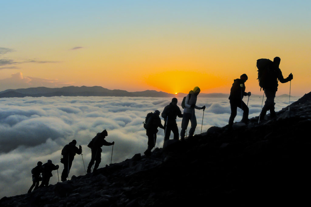 Several people hiking up a mountain side.