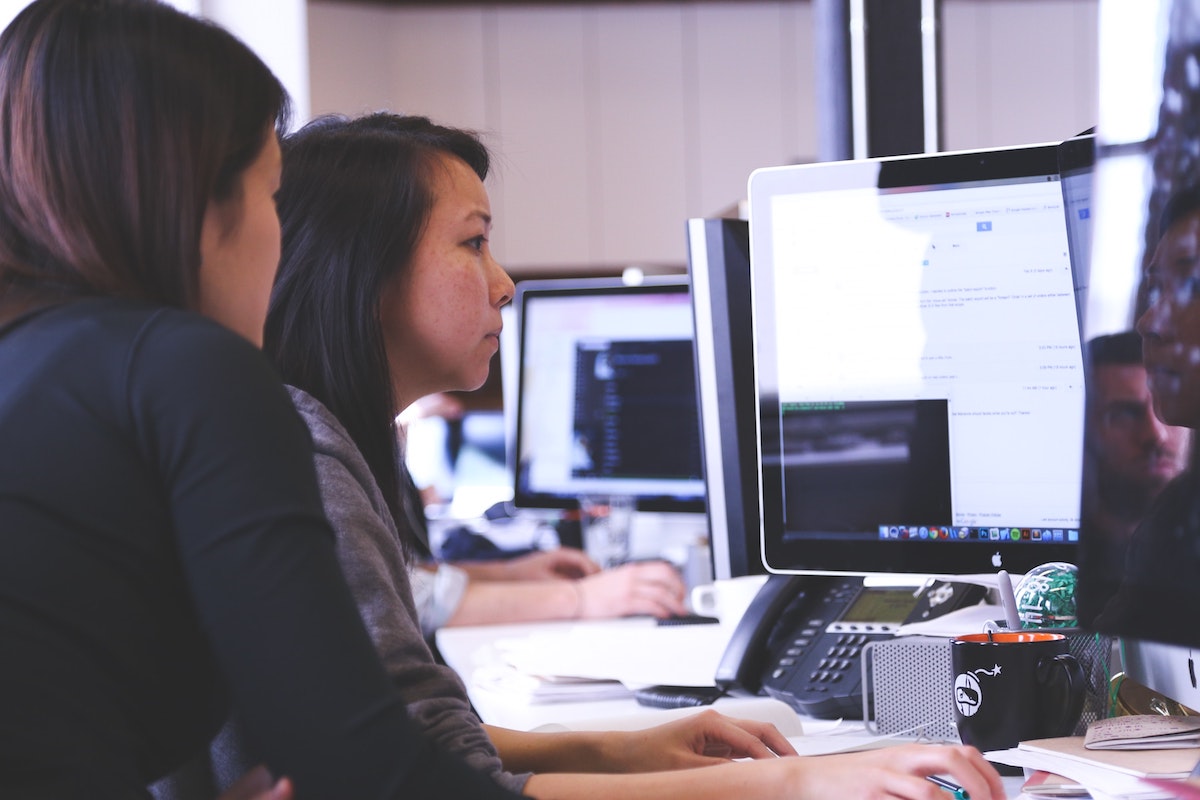 2 women working at coding in an office.