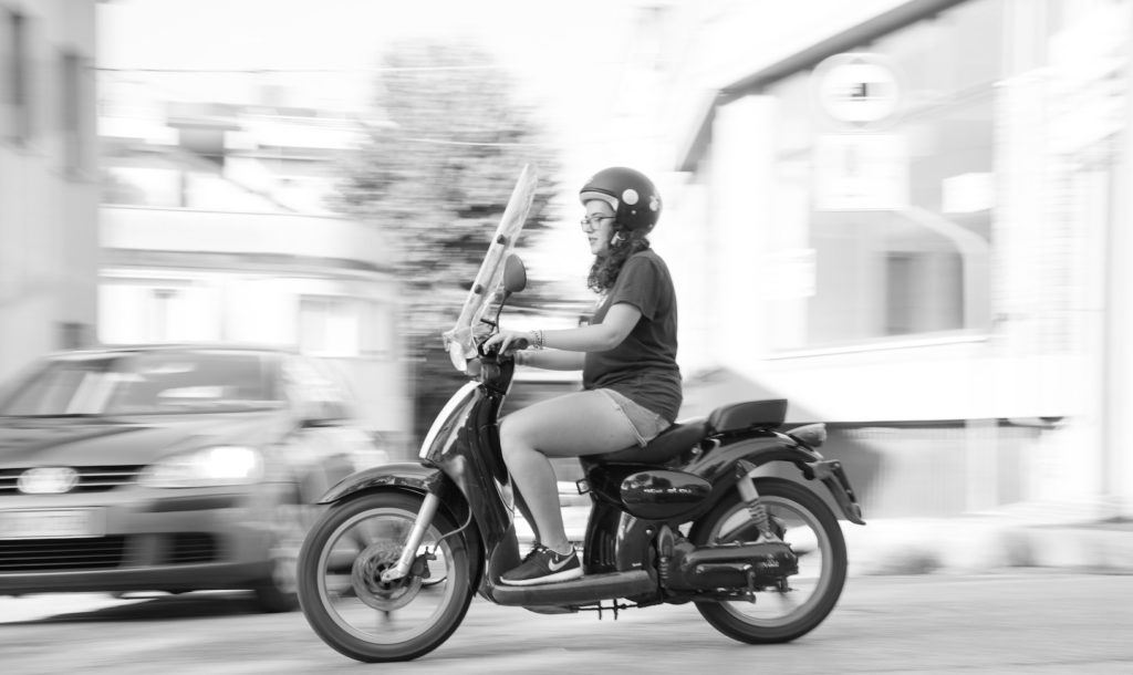 A woman riding a vespa.