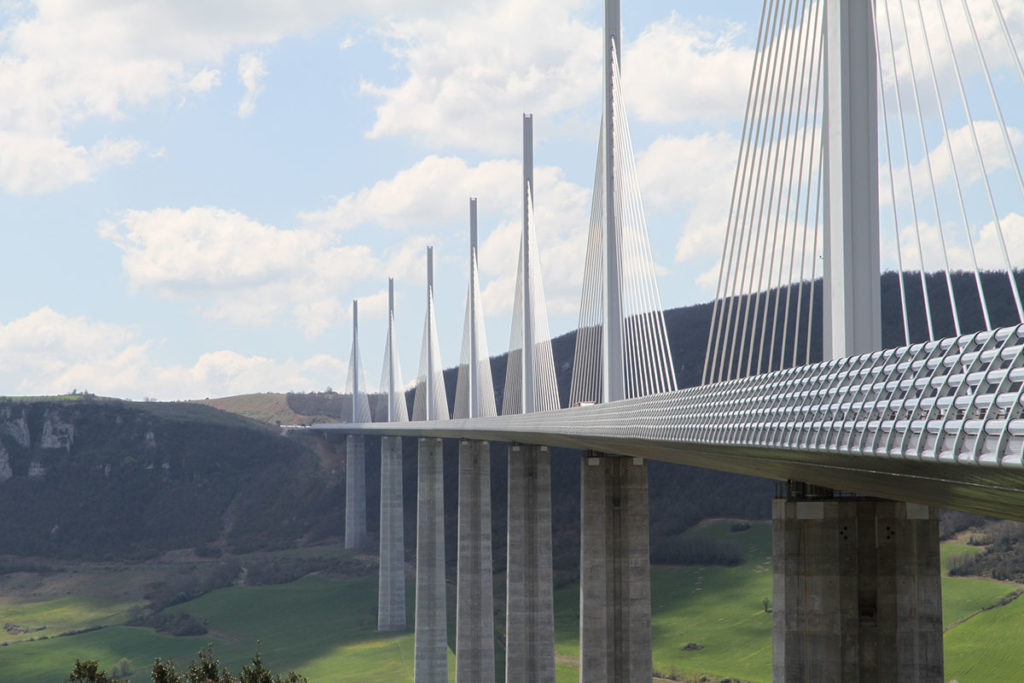 The Millau Viaduct is a multispan cable-stayed bridge which spans a large, green valley.