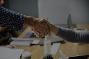 A man and a woman shaking hands in an office.