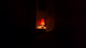 A small, red lamp in the window of a house.