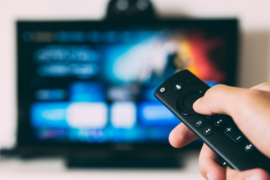 A person pointing a remote at a TV.