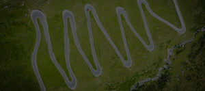 A winding road with hairpin turns, going up the side of a hill.