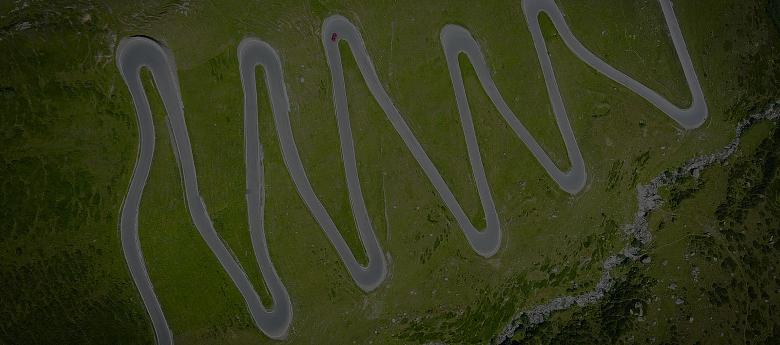 A winding road with hairpin turns, going up the side of a hill.