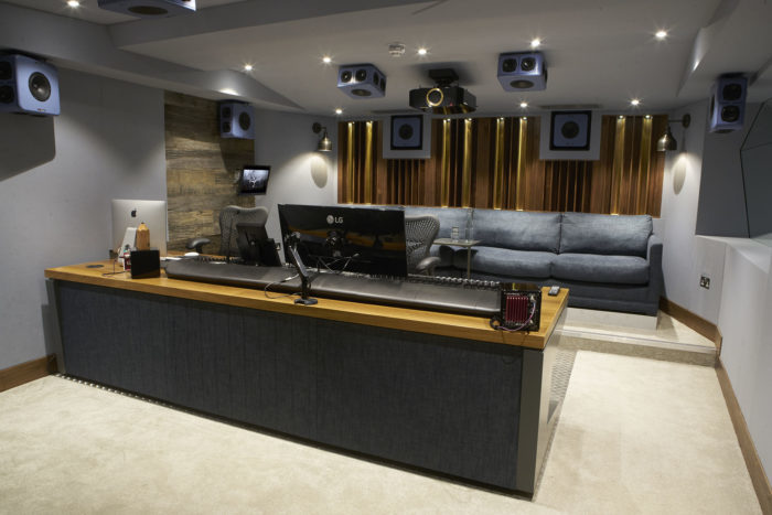 The Envy Dolby Atmos Studio with a couch, lots of speakers and soundboard and computer.