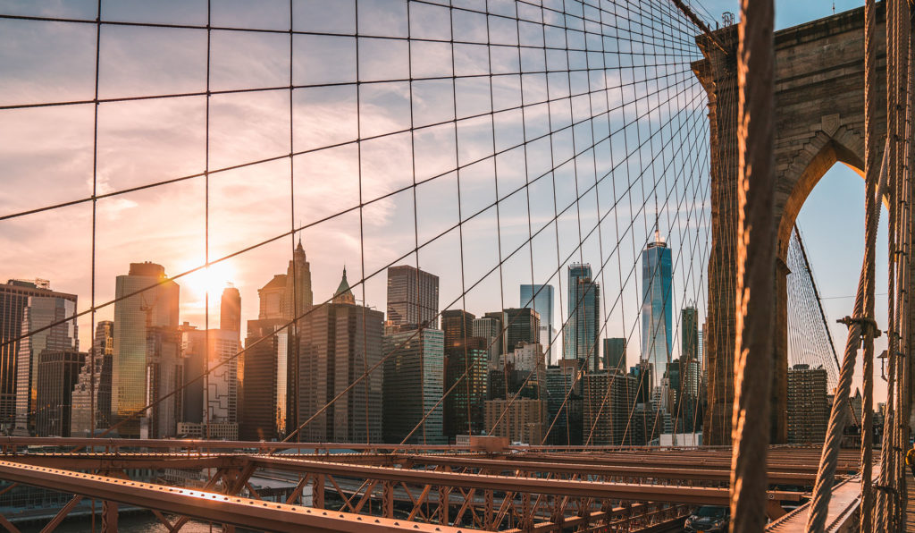 The New York City skyline seen through the trellis of a bridge.