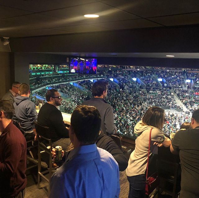 People watching a sporting event from a box at the top of a stadium.