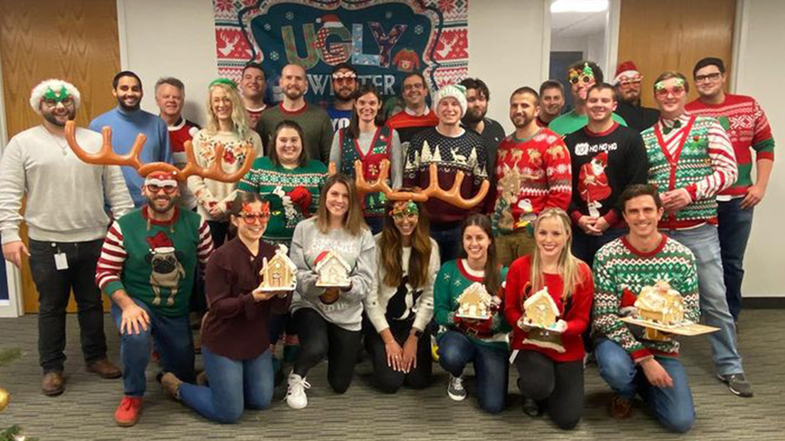 Signiant employees dressed in Christmas sweaters and holding gingerbread houses they had made.