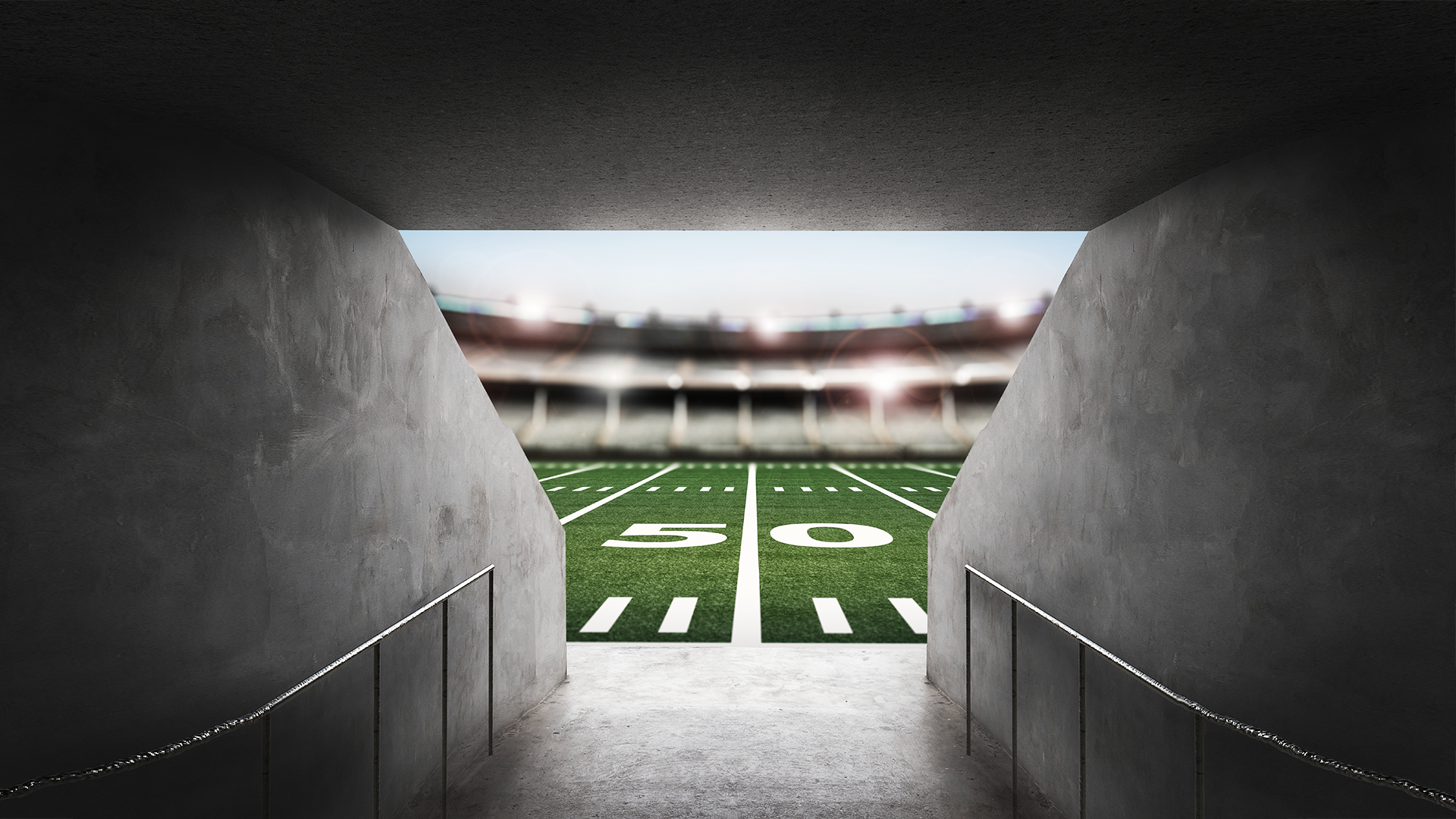 A tunnel leading to a stadium football field at the 50 yard line