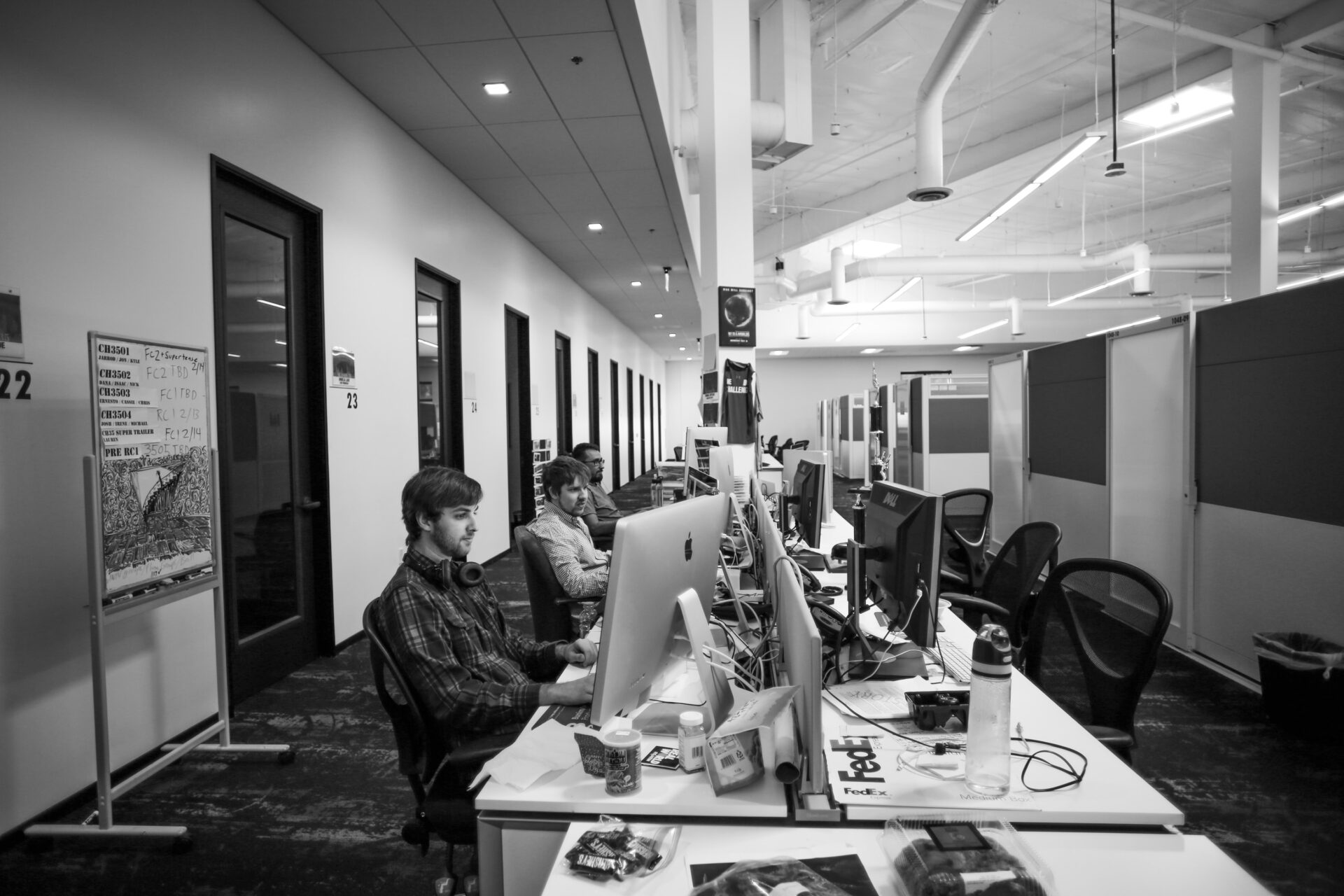 A shot of three men at a long desk with their computers